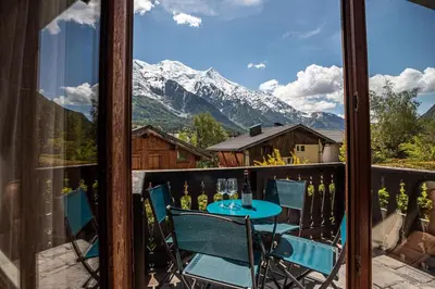a balcony with a table and chairs and a mountain at APARTMENT CHAMOUNY - Alpes Travel - Chamonix - Sleeps 8 in Chamonix-Mont-Blanc