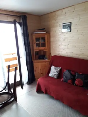a bedroom with a red bed and a wooden wall at appart st gervais le Topaze in Saint-Gervais-les-Bains