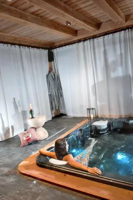 a woman laying in a hot tub in a room at Chalet spacieux à Samoëns de 210 m² avec jacuzzi et jardin in Samoëns
