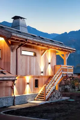 a wooden house with a staircase on the side of it at Chalet spacieux à Samoëns de 210 m² avec jacuzzi et jardin in Samoëns