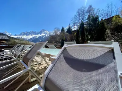 a row of chairs and a table on a deck at Chalet 4C in Les Houches