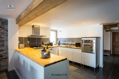 a kitchen with white cabinets and a wooden counter top at Les Iles 1776 in Chamonix-Mont-Blanc