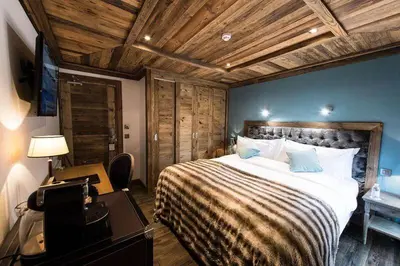 a bedroom with a large bed with a wooden ceiling at Le Chalet Blanc in Megève
