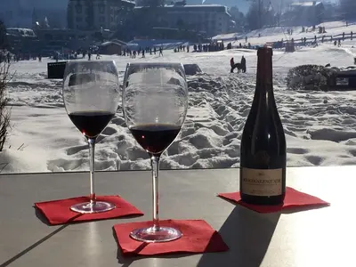 two glasses of wine sitting on a table with a bottle of wine at Front Ski Slope Chamonix Apartment in Chamonix-Mont-Blanc