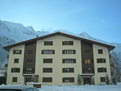 a large building with snow in front of a mountain at Apartment Le Cristal des Glaces by Interhome in Chamonix-Mont-Blanc