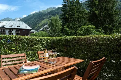 a wooden table with two chairs and wine glasses at Apartment Jonquille Terrasse Centre Chamonix Mont Blanc in Chamonix-Mont-Blanc