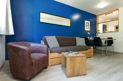 a living room with a couch and a blue wall at Apartment Jonquille Terrasse Centre Chamonix Mont Blanc in Chamonix-Mont-Blanc