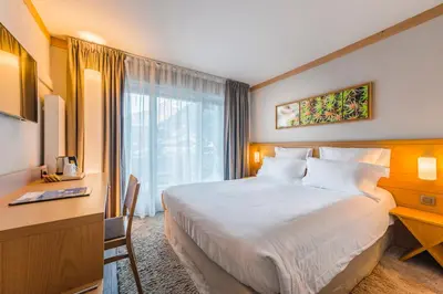 a hotel room with a large bed and a desk at Hotel Le Morgane in Chamonix-Mont-Blanc