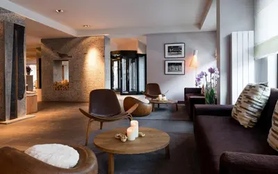 a living room with couches and chairs and a fireplace at Hotel Le Morgane in Chamonix-Mont-Blanc