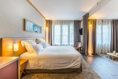 a hotel room with a large white bed and windows at Hotel Le Morgane in Chamonix-Mont-Blanc