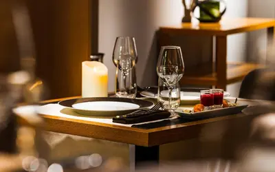 a table with a candle and wine glasses on it at Hotel Le Morgane in Chamonix-Mont-Blanc