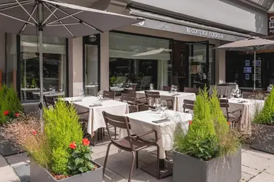 an outdoor restaurant with tables and chairs and umbrellas at Hotel Le Morgane in Chamonix-Mont-Blanc