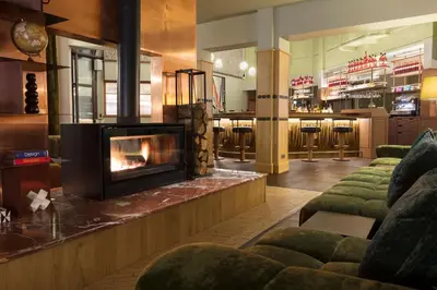 a living room with a fireplace in the middle at Hôtel Les Aiglons Chamonix in Chamonix-Mont-Blanc
