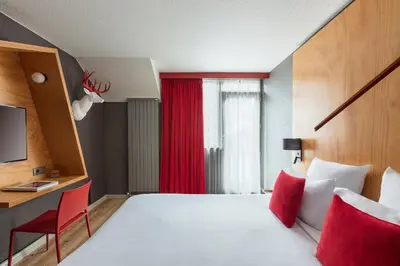 a hotel room with a large bed and a red window at Hôtel Les Aiglons Chamonix in Chamonix-Mont-Blanc