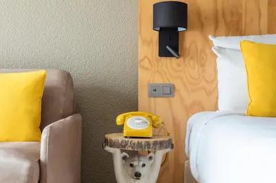 a bedroom with a bed and a yellow phone on a side table at Hôtel Les Aiglons Chamonix in Chamonix-Mont-Blanc