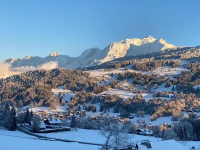 a village covered in snow with mountains in the background at Ferme Vauvray in Megève