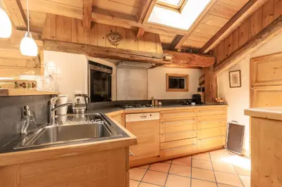 a kitchen with a stainless steel sink and wooden cabinets at Ferme Vauvray in Megève