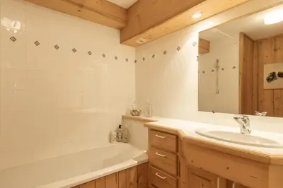 a bathroom with a tub and a sink and a tub and a mirror at Ferme Vauvray in Megève