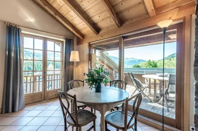 a dining room with a table and chairs and a balcony at Ferme Vauvray in Megève