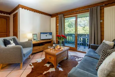 a living room with couches and a tv and a table at Ginabelle 14 apartment - Chamonix All Year in Chamonix-Mont-Blanc