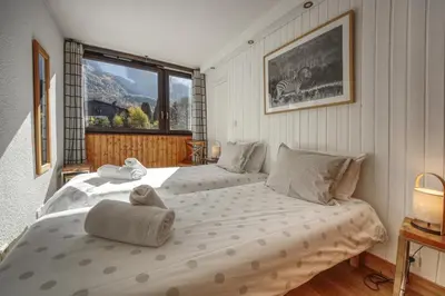 a bedroom with two beds and a large window at Apartment Scott in Chamonix-Mont-Blanc