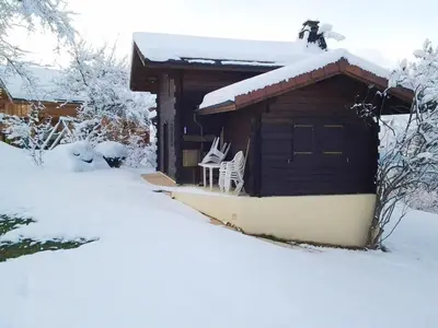 a cabin with snow on the roof and two chairs in the snow at Chalet confortable à Saint-Gervais-les-Bains 60 m² vue montagne in Saint-Gervais-les-Bains
