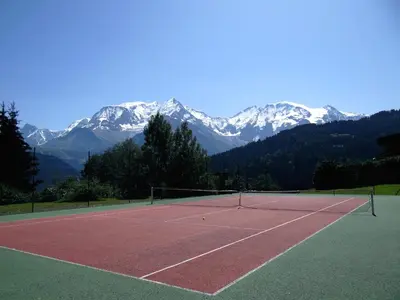 a tennis court with snow capped mountains in the background at Duo Des Alpages vue exceptionnelle sur le Mont Blc in Saint-Gervais-les-Bains