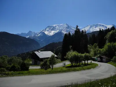 a road with a house and mountains in the background at Duo Des Alpages vue exceptionnelle sur le Mont Blc in Saint-Gervais-les-Bains