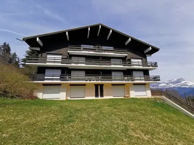 a large building on top of a grassy hill at Duo Des Alpages vue exceptionnelle sur le Mont Blc in Saint-Gervais-les-Bains