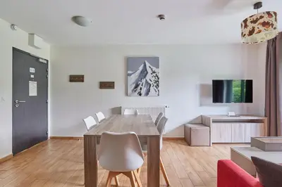 a living room with a wooden table and chairs at Résidence Odalys Isatis in Chamonix-Mont-Blanc