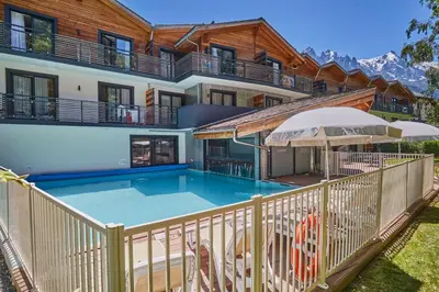 a house with a swimming pool in front of a house at Résidence Odalys Isatis in Chamonix-Mont-Blanc