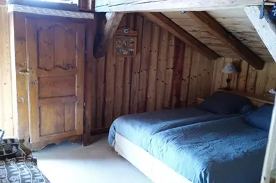 a bedroom with two beds and a wooden wall at Chambre d'Hôtes La ferme d'en bas in Samoëns