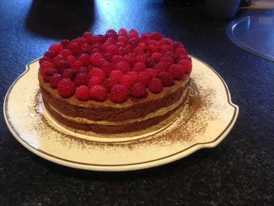 a cake with raspberries on top on a plate at Chambre d'Hôtes La ferme d'en bas in Samoëns