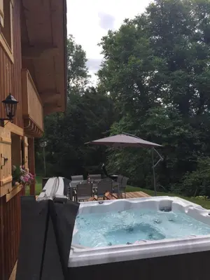 a hot tub with an umbrella on a patio at Chalet Lilalpes SPA in Samoëns