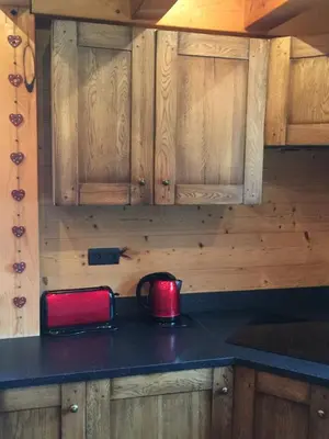a kitchen with wooden cabinets and a red kettle on a counter at Chalet Lilalpes SPA in Samoëns