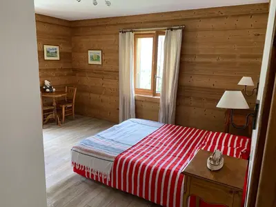 a bedroom with a bed and a table and a window at Le Chalet dans les Etoiles in Samoëns