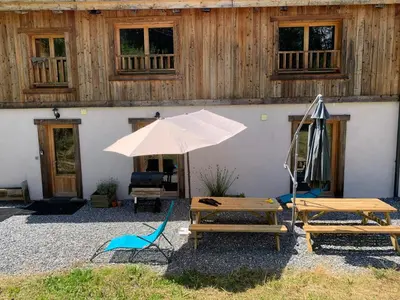 a patio with a table and an umbrella and a chair at Le Chalet dans les Etoiles in Samoëns