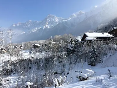 a snow covered village with mountains in the background at Facing the Chamonix Needles in Les Houches