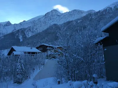 a snow covered mountain with a house and trees at Facing the Chamonix Needles in Les Houches
