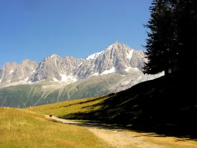 a dirt road in front of a snow covered mountain at Facing the Chamonix Needles in Les Houches