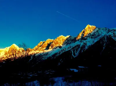 a snow covered mountain with the sun shining on it at Facing the Chamonix Needles in Les Houches