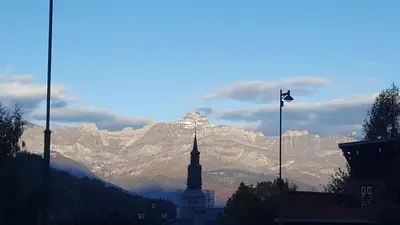 a mountain in the distance with a building and a flag at Duplex Les Périades 18 in Saint-Gervais-les-Bains