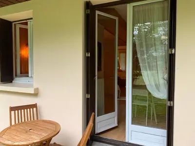 a glass door leading to a patio with a wooden table at Chamonix Studio Jardin in Chamonix-Mont-Blanc