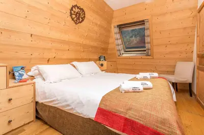 a bedroom with a bed and a chair in a cabin at Le Paradis 18 & 18b appts - Chamonix All Year in Chamonix-Mont-Blanc