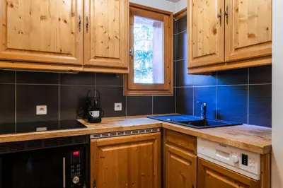 a kitchen with wooden cabinets and a sink at Les Balcons du Savoy in Chamonix-Mont-Blanc