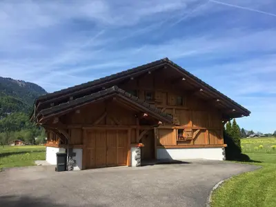 a large wooden building in a field at Chalet Pétérets in Samoëns