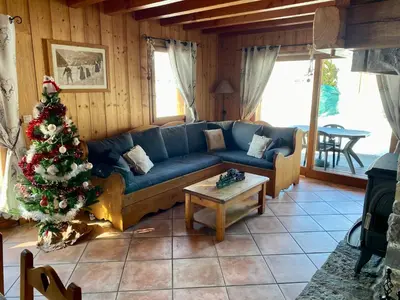 a living room with a blue couch and a christmas tree at Chalet Pétérets in Samoëns
