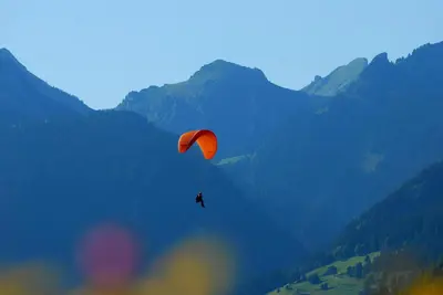 a person riding a parachute in the mountains at Chalet Clos Moccand in Samoëns