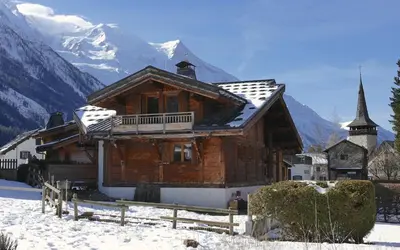 a wooden house in the snow with a church at LES 3 CIMES BLANCHES in Chamonix-Mont-Blanc