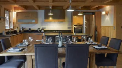 a kitchen with a wooden table with chairs around it at LES 3 CIMES BLANCHES in Chamonix-Mont-Blanc